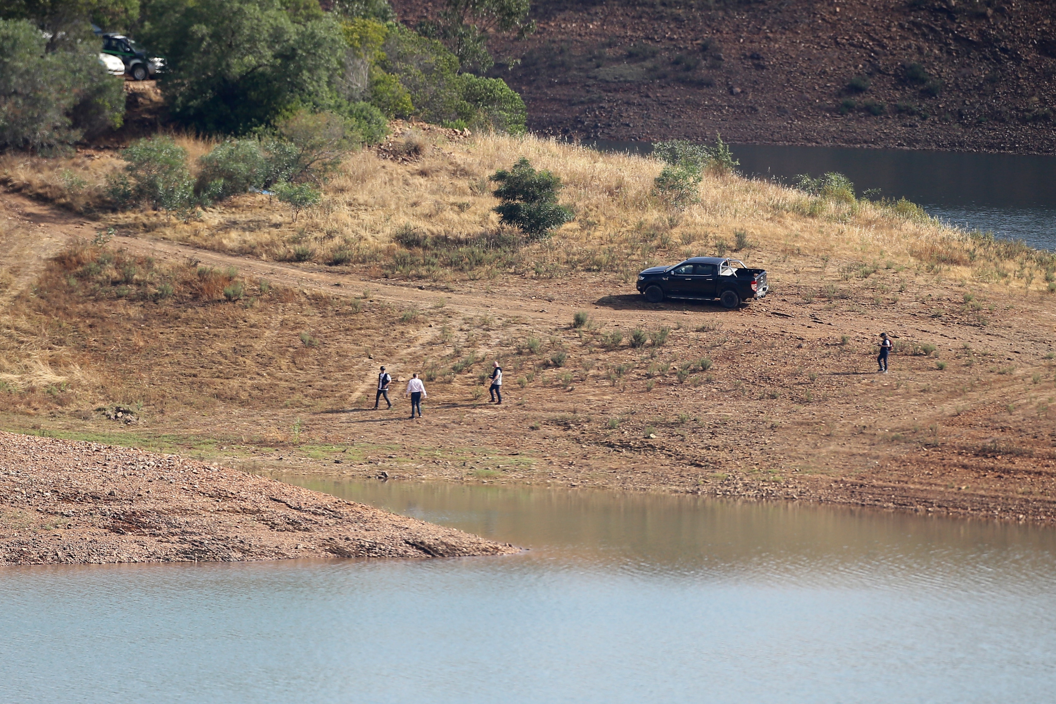 A view of a dam with police and vehicle in distance.