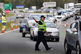 A Queensland police officer directs traffic as motorists queue at a border checkpoint at Coolangatta on the Gold Coast.