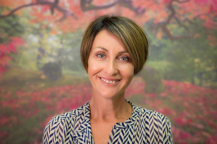 A woman with a bob haircut in front of a colourful studio backdrop