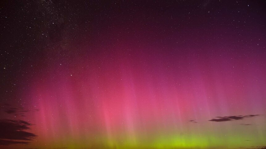 Red and green coloured lights - an aurora -  in the night sky