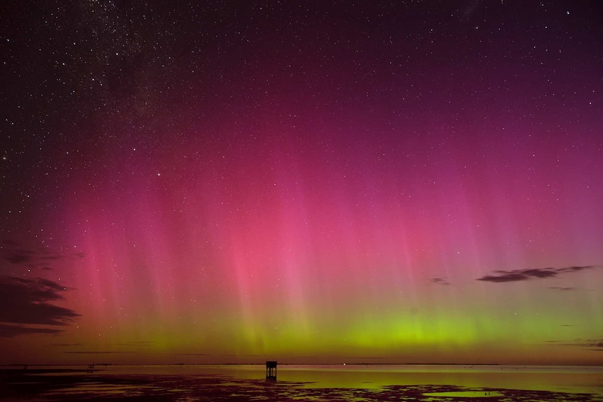 Red and green coloured lights - an aurora -  in the night sky