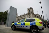 A police four-wheel-drive stands guard by a boarded up statue in London.