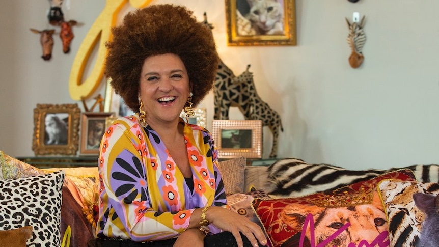 A male comedian dressed up as an African woman with an afro wig and fake tan