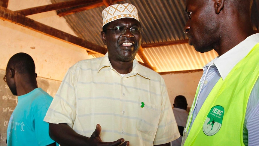 Malik Obama talks to a polling official after voting.