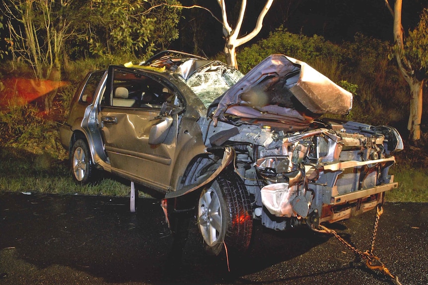 The badly mangled wreckage of a grey car. 