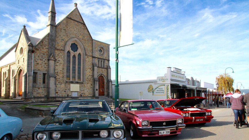 Classic cars on a street in front of a church