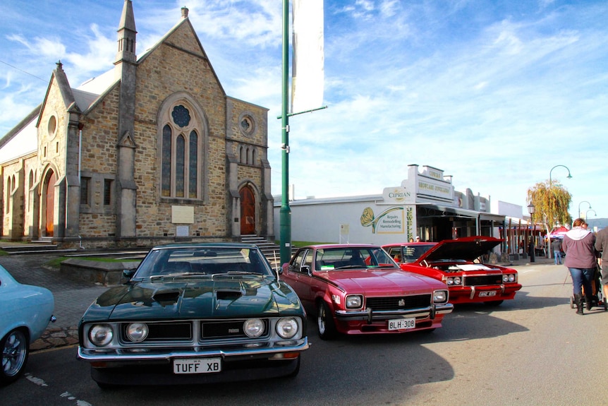 Classic cars on a street in front of a church