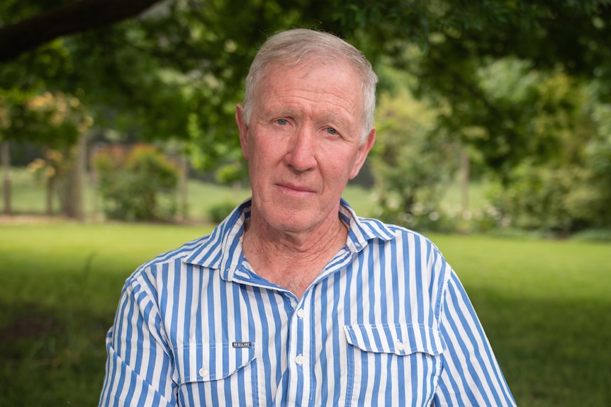 Portrait of man in his 60s in a stripey shirt in a green paddock