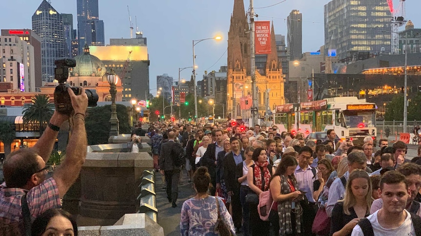 Passengers queue across Princes Bridge in Melbourne