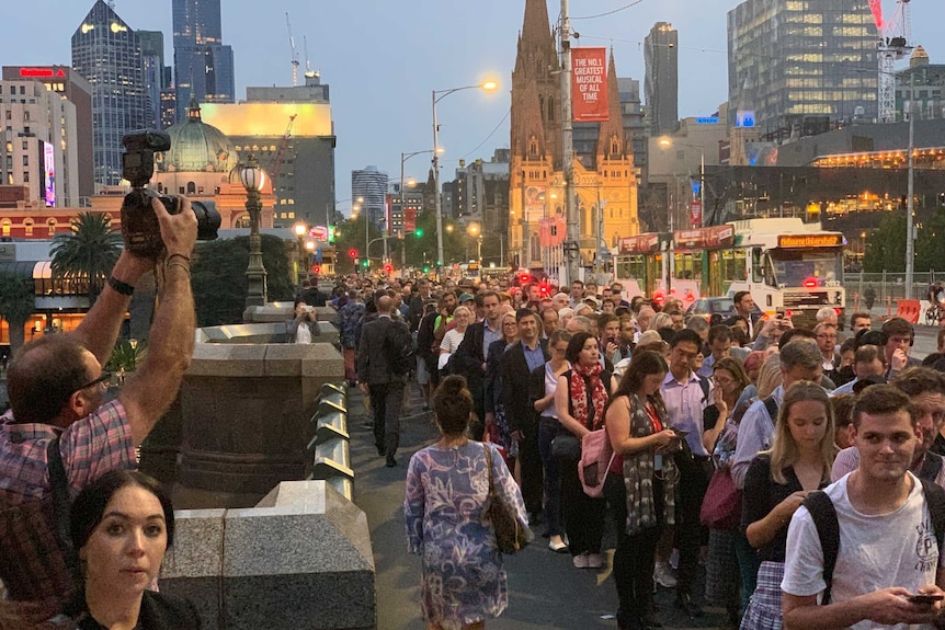 Passengers queue across Princes Bridge in Melbourne