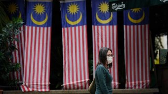 A woman walks in front of Malaysian flags