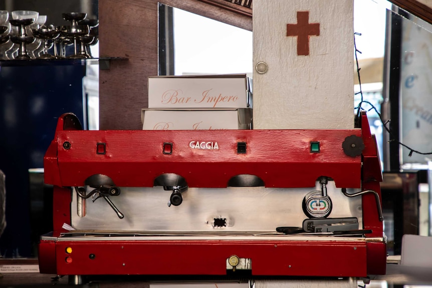 A red espresso machine sits on a bench