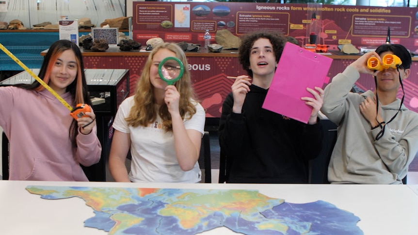 High school students hold up geography instruments in a classroom