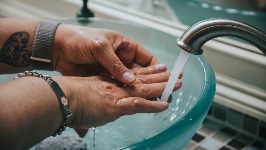 Hands under a running tap.