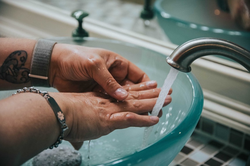 Hands under a running tap.