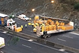 A trailer of a truck with yellow crates spilled over a road