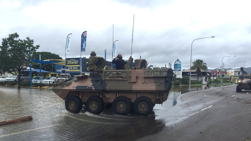 An army tank enters a flooded street in Townsville.