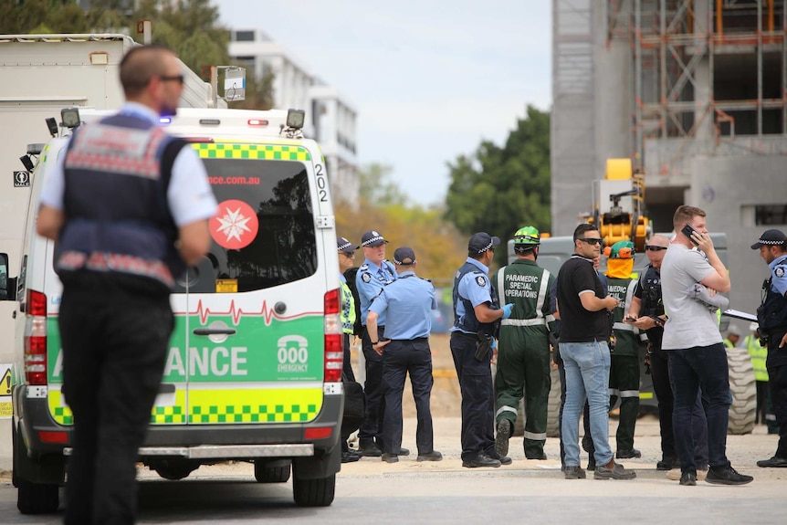 Police officers, paramedics and witnesses stand near an ambulance at the site of a roof collapse at Curtin University.