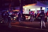 Police officers surround a group of men outside a Broadbeach restaurant.