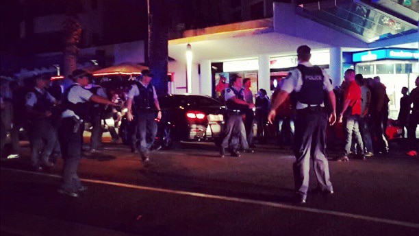 Police officers surround a group of men outside a Broadbeach restaurant.