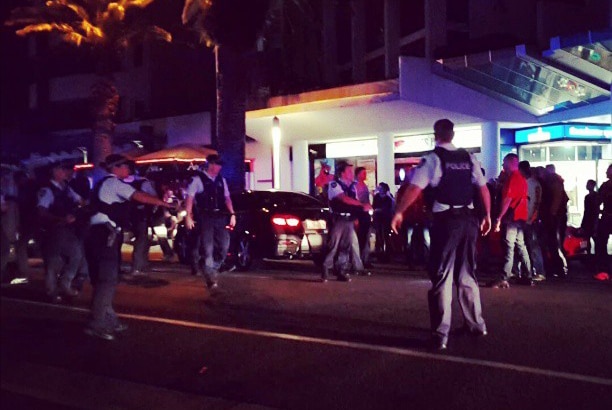 Police officers surround a group of men outside a Broadbeach restaurant.