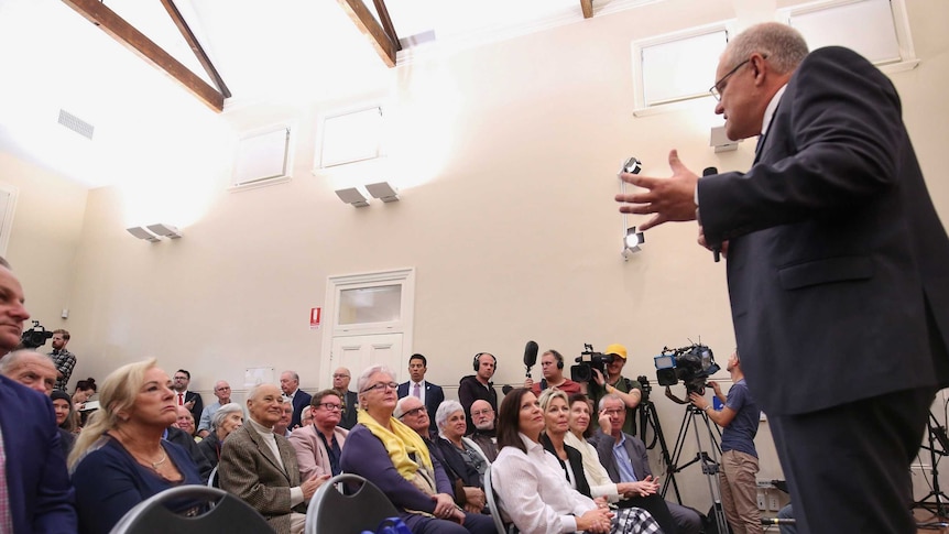 a group of predominately elderly people look to Scott Morrison who is speaking into a microphone in front of them