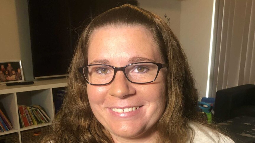 Jenna Hitchcock sits in her loungeroom at home. She is wearing glasses