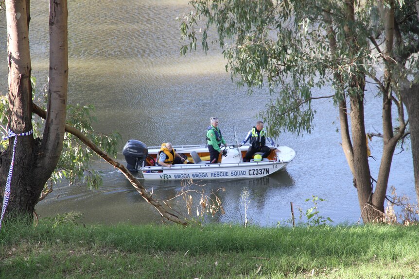 A small rescue boat crewed by police makes its way down a river.