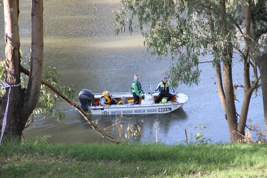 A small rescue boat crewed by police makes its way down a river.