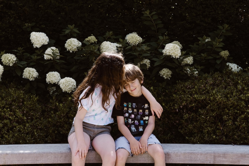 Girl with arm around younger child