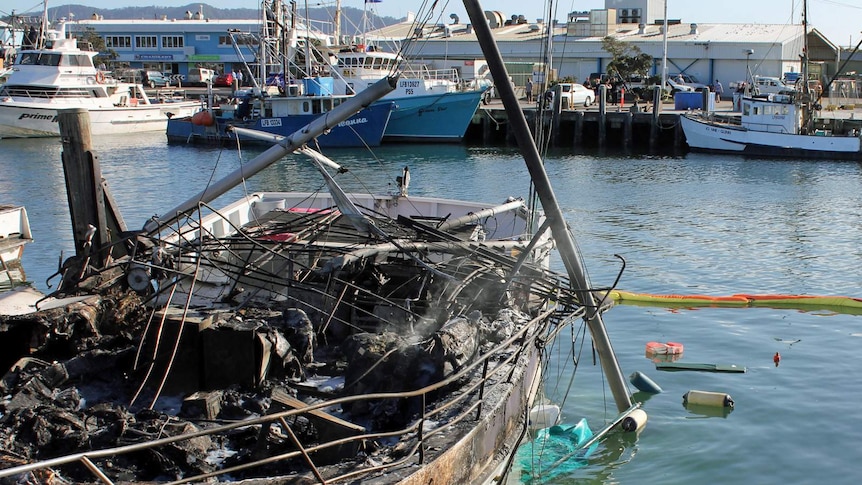A burnt-out fishing trawler smoulders in Coffs Harbour