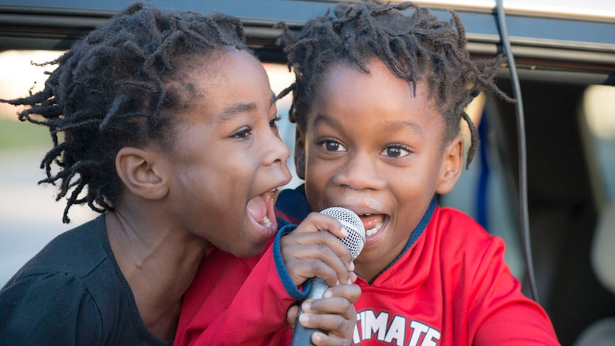 Two kids talking into a microphone