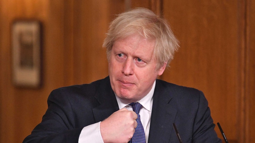 Britain's Prime Minister Boris Johnson holds his fist near his chest as he speaks.