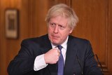 Britain's Prime Minister Boris Johnson holds his fist near his chest as he speaks.