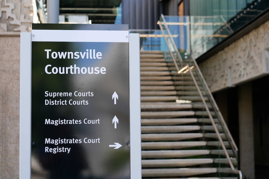 A sign that says "Townsville Courthouse" in front of a building and a flight of stairs.