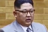 Kim jong-un stands behind microphones and makes New Year address.