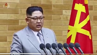 Kim jong-un stands behind microphones and makes New Year address.