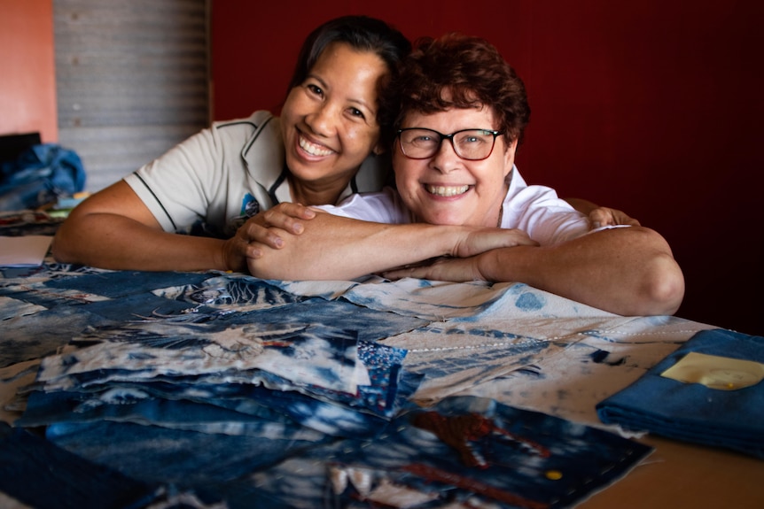A portrait of two women in front of patches for a community quilt.