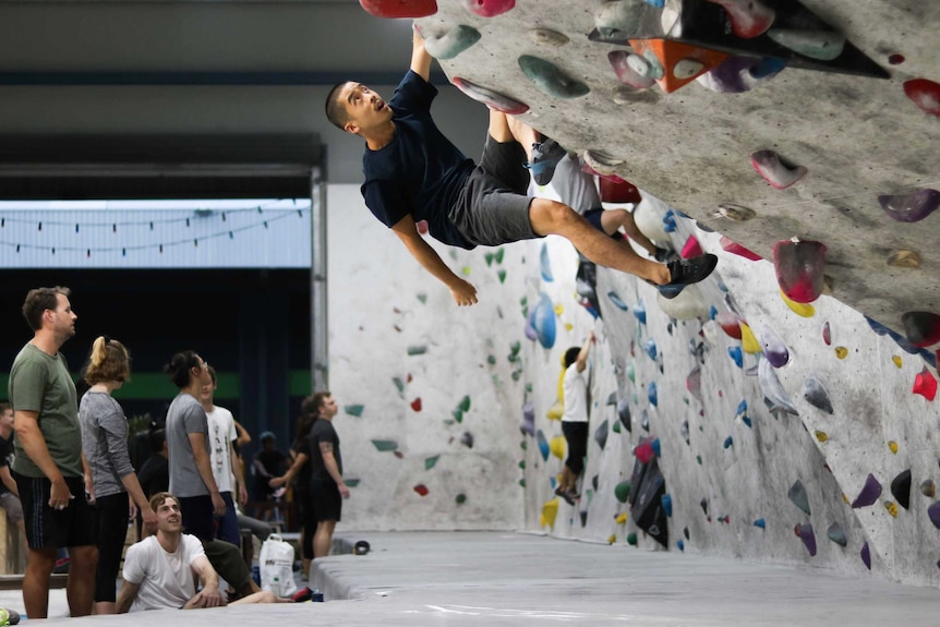 A climber hangs from the walls of the 9 Degrees bouldering gym in Sydney.