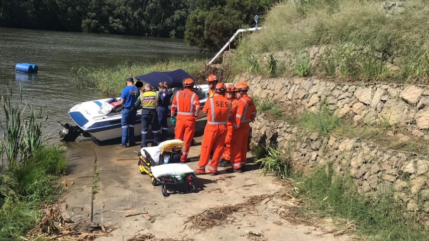 A small boat crashed into an embankment surrounded by SES and ambulance workers.