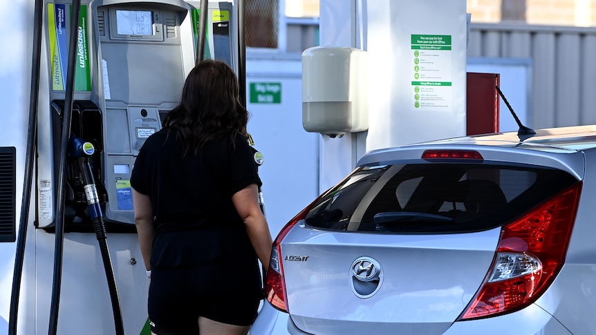 A woman fills up a car with petrol