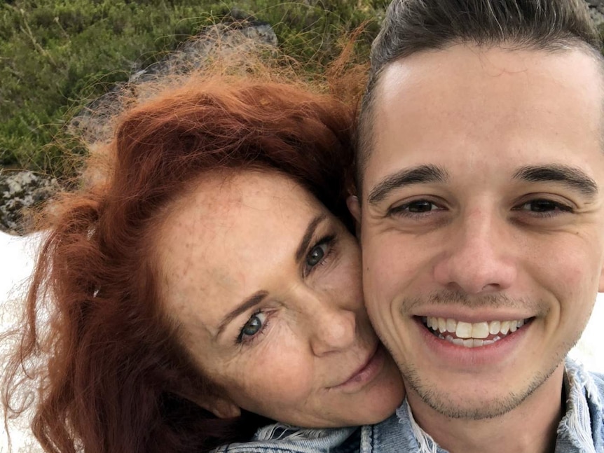 A selfie photo of a mature red-haired woman and a younger man who has styled hair and facial stubble