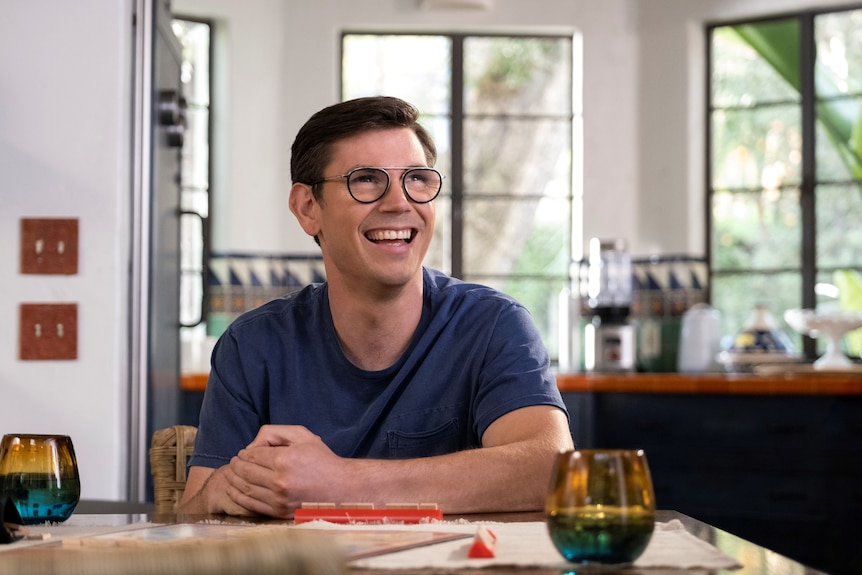 A scene from Netflix series Special of a young man with glasses sitting at a table in a cafe