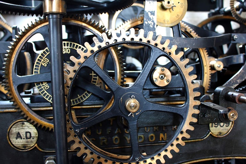 A close-up of large black and gold cogs that run a clock tower.