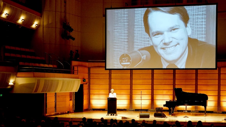 Shot from back of the auditorium with Mark Colvin's picture largely projected.