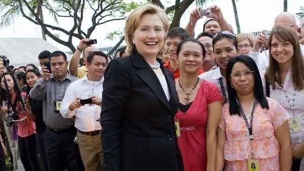 Hillary Clinton in a dark suit meets with staff at the US Embassy in Manila