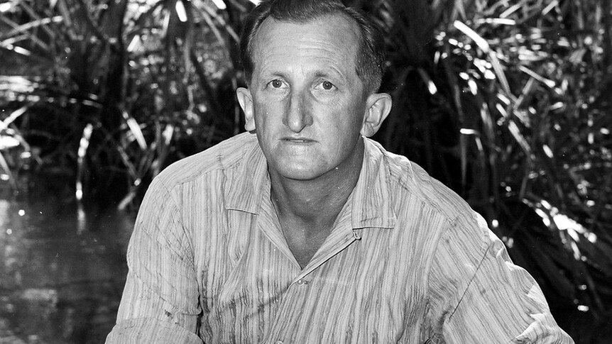 A black-and-white photo of croc hunter Ron Pawlowski sitting at his desk.