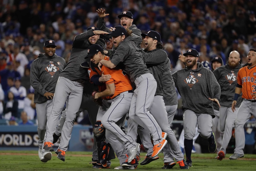 Astros players jump and hug after winning the game.