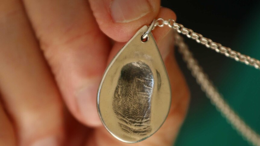 a woman's hand holding a pendant