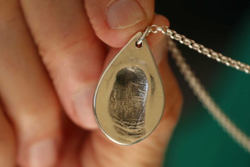 A woman's hand holding a pendant